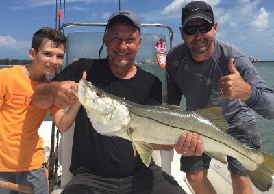 Salty Water Fishing Charters, Captain Jimmy hartley fishing with customers with kid holding snook